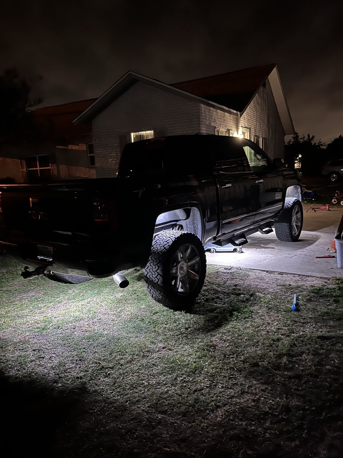 Custom lifted GMC truck with aftermarket wheels at night
